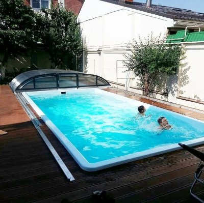 Прямоугольный бассейн с прозрачным поликарбонатным укрытием и людьми в воде